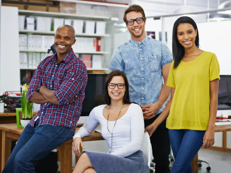 A diverse group of four office team members smiling and standing together for business directory